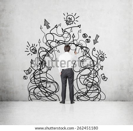 businessman with drawing arrows and business symbol on wall