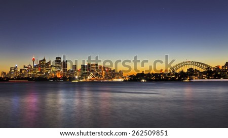 Australian Sydney landmarks - and harbour bridge at sunset in panoramic view when bright city lights reflecting in harbour water