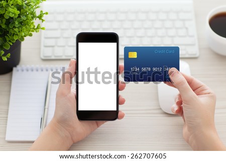 female hands holding phone with isolated screen and a credit card over the desk in the office Royalty-Free Stock Photo #262707605