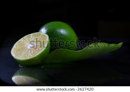a lemon and half with leaf on the black background