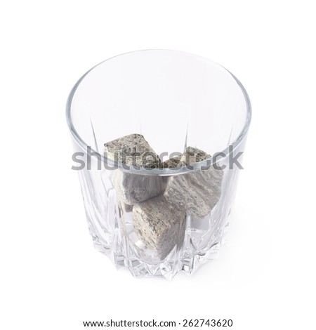 Empty whiskey tumbler glass filled with cooling granite stones isolated over the white background