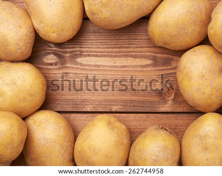 Frame made of fresh washed potatoes over the wooden table's surface as a copyspace background composition