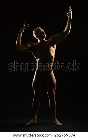 Athletic muscular man posing over black background. Men's beauty. Bodybuilding. Sports. 