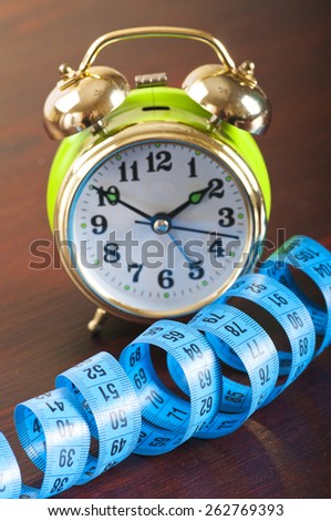 measuring tape and alarm clock on the wooden background