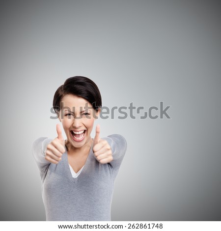 Merry girl gives thumb up, isolated on grey