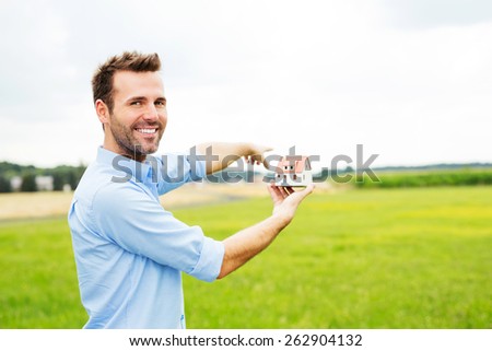 Happy man with miniature showing place on field for new house