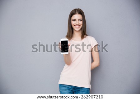 Happy young woman showing blank smartphone screen