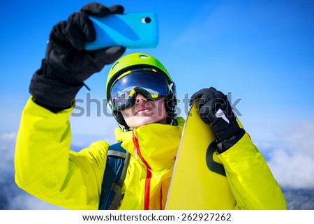 Man in winter clothes taking a selfie with skis