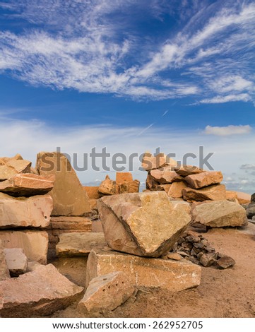 Large rock pile brown, which is located on the sand under a cloud sky beautiful.