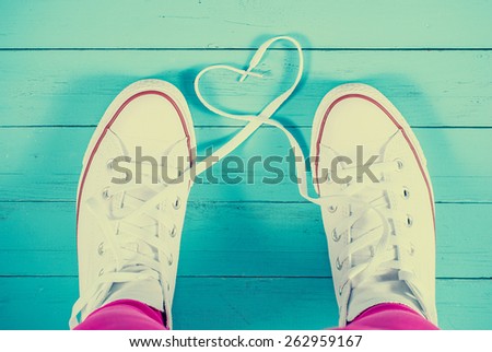 White sneakers with heart on blue wood background, filtered image