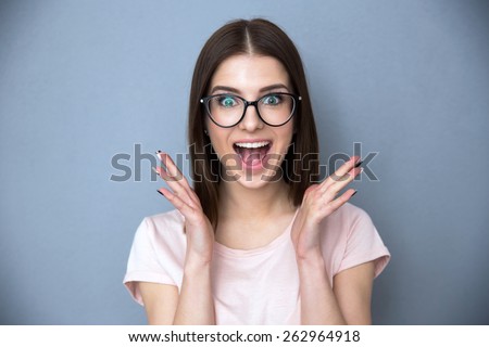 Surprised young woman in glasses over gray background Royalty-Free Stock Photo #262964918