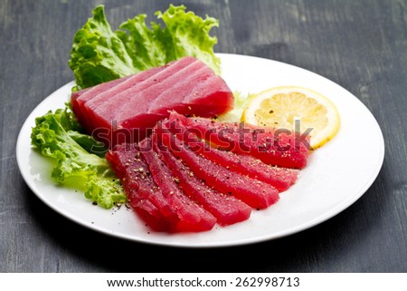 Slices of raw bluefin tuna  sashimi on white dish on wood background