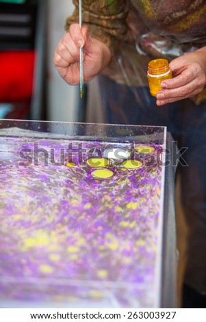 Woman hands with paintbrush marbling on water