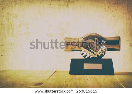 decorative handshake gadget over wooden table. business concept. image is retro filtered