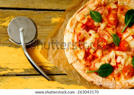 Tasty pizza and knife on an old paper. On a wooden background.