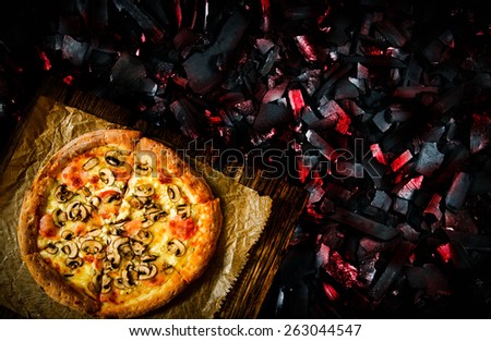 Pizza on a wooden board. Concept pizza prepared on coals.