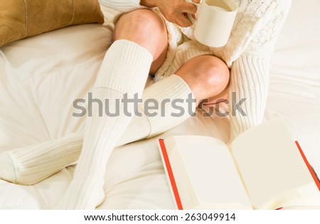 Woman in bed reading and relaxing with a cup of milk