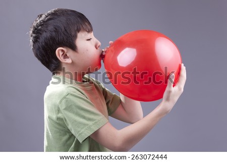 Boy blows up balloon. Royalty-Free Stock Photo #263072444