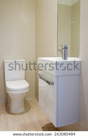 Angled view of newly renovated fully tiled bathroom toilet and basin