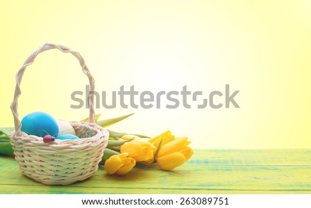 Beautiful Easter eggs in a basket. Delicate yellow spring tulips. Spring Easter holidays. Wooden board rustic