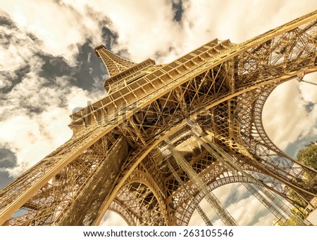 Eiffel Tower bottom view, Paris, France. Openwork construction on sky background. Famous design of World landmark. Theme of travel, tourism and sightseeing. Vintage style photo.