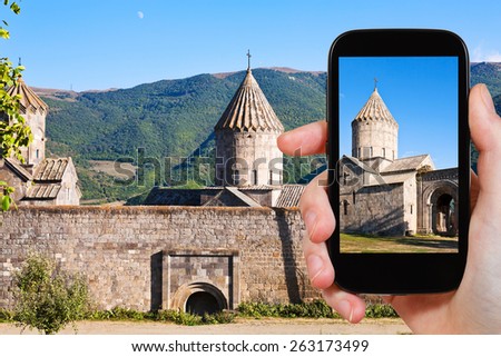 travel concept - tourist takes picture of st. paul and peter cathedral in Tatev Monastery in Armenia on smartphone,