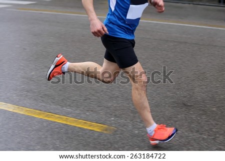 strong muscular legs of the athlete during the road race with rain, motion blur