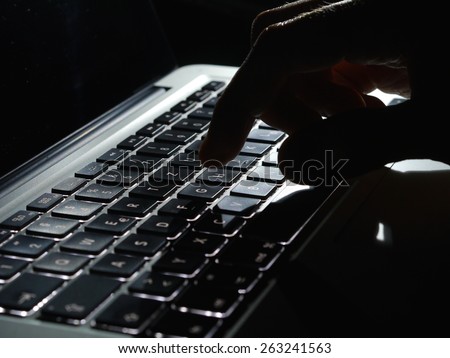 Cybercrime - lighted keayboard hand in the dark Royalty-Free Stock Photo #263241563
