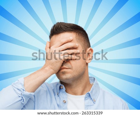 stress, headache, health care and people concept - unhappy man covering his eyes by hand over blue burst rays background