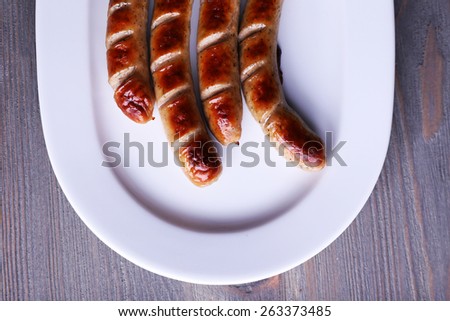 Grilled sausages on plate on table close up