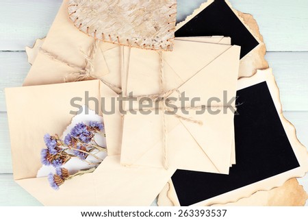 Old envelopes with photo papers and dry flowers on wooden background