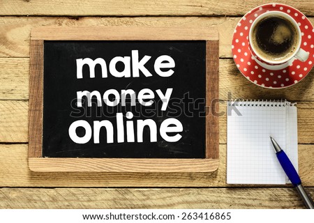 Make money online on blackboard. Make money online On blackboard with cup of coffee, notebook and pen on wooden background