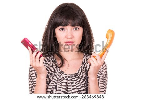 beautiful young woman using retro orange telephone and mobile phone looking clueless isolated on white
