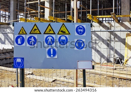 The metal stand with the standard warning signs of labor protection and health on building