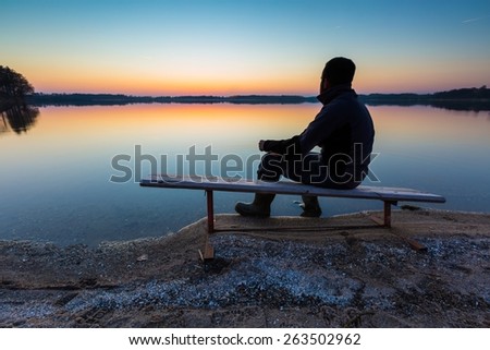 Man in lake water at sunset. Beautiful sunset with man silhouette