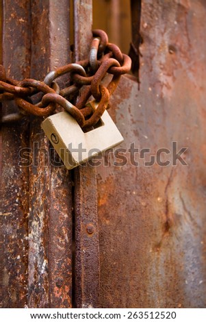 Rusty metal gate closed with padlock 