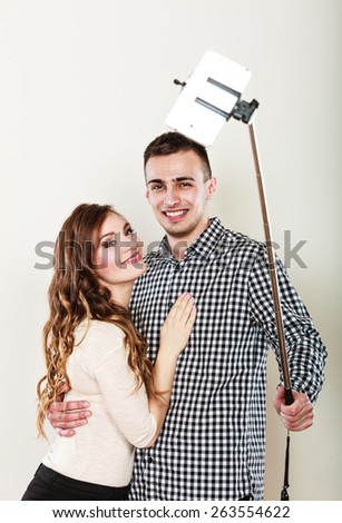 Technology internet and happiness concept. Young couple taking self picture selfie with smartphone camera gray background