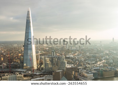 Aerial view of London with The Shard skyscraper and Thames river at sunset with grey clouds in the sky