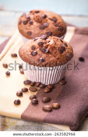 two fresh chocolate muffins  and grains of coffee, in a studio