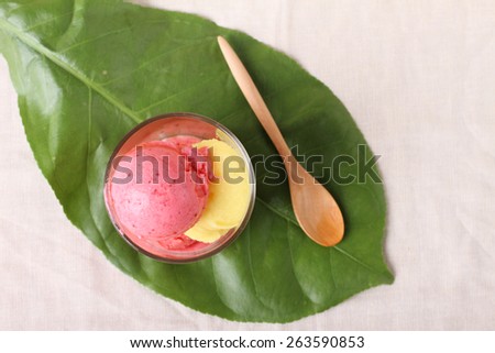 strawberry and passion fruit sherbet in a glass, green leaf background