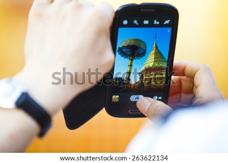 A tourist taking pictures of a temple in Chiang Mai, Thailand.