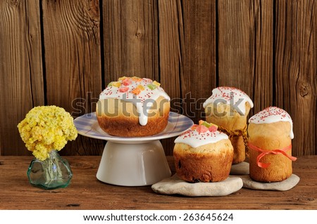 Kulich, Russian easter sweet breads decorated with icing and candied fruits with yellow flowers on wooden background