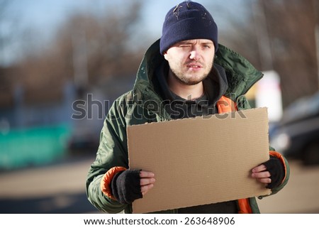 Homeless man holds blank cardboard for your own text
