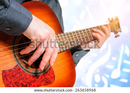 Male hand plucking guitar strings with fingers.