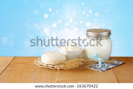 Tzfatit cheese , cottage and milk on wooden table over blue glitter background. Symbols of jewish holiday  - Shavuot