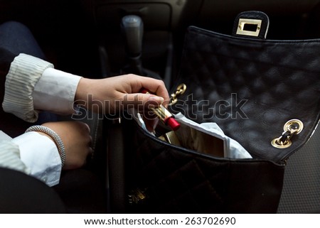 Closeup photo of businesswoman taking red lipstick out of handbag