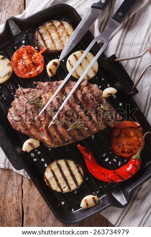 beef steak grilled with onions and eggplant on the grill pan closeup. Vertical view from above 