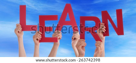 Many Caucasian People And Hands Holding Red Letters Or Characters Building The English Word Learn On Blue Sky