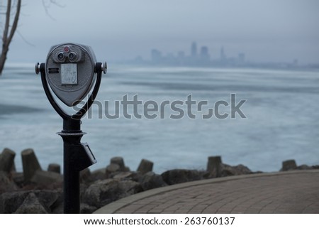 Close-up of a coin operated binoculars on an observation deck looking towards a large city.