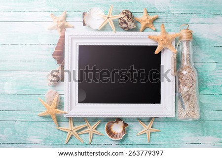 Marine items and empty blackboard  on turquoise painted wooden background. Sea objects - shells, sea stars on wooden planks. Selective focus. 